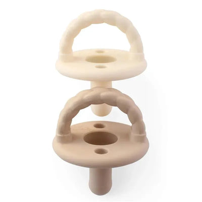 Silicone pacifier set in Toast and Buttercream Braids colors, featuring two textured handles and round shapes.