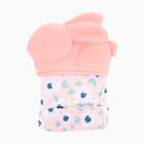 Teething mitt in the shape of a pink bunny, featuring a floral fabric and attached tag, designed for babies.