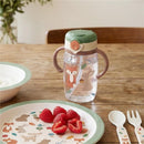 Woodland-themed straw cup featuring a fox and rabbit design, with a snap-close lid, placed beside a plate of raspberries.