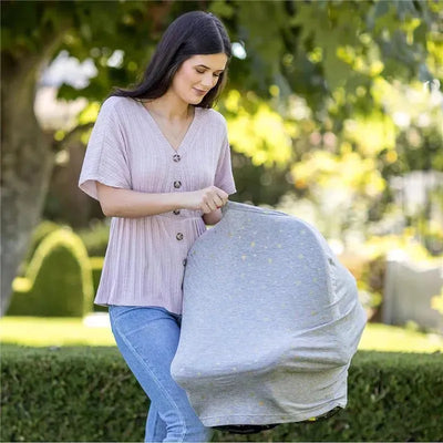 Stretchy car seat canopy in grey with gold stars used by a woman in a light top while outdoors.