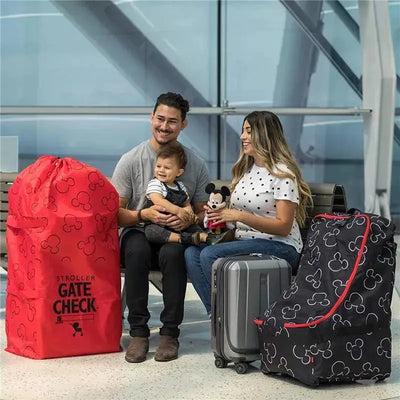 Red and black J.L. Childress Gate Check Bags for strollers with Mickey Mouse print, a family sitting in an airport.