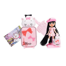 Mini doll wearing a pink dress and beret, next to a cat-themed suitcase and a postcard with Paris imagery.