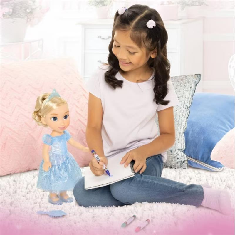 A young girl with curly hair plays with a 14-inch Cinderella doll, drawing in a notebook on a fluffy carpet.