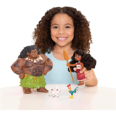 Child holding a Moana doll and Maui figure, with a small pig and rooster on the table, smiling and playing.