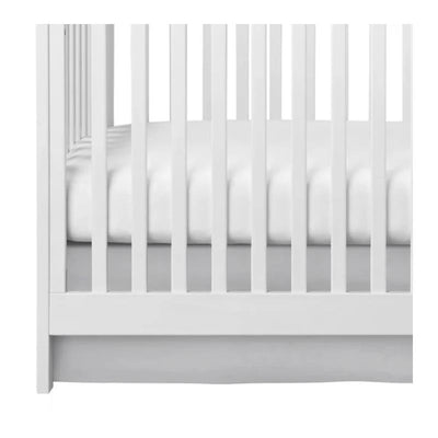 Gray crib skirt fitted under a white crib, complementing the bedding with a clean, modern design.