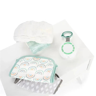 Kids II Ingenuity Pock-a-Bye Baby Soother and Bluetooth speaker with play and volume buttons, surrounded by a blanket and other baby items.