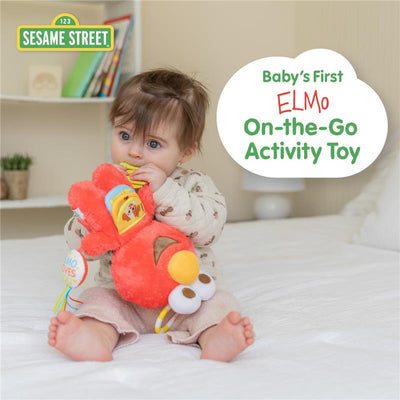 Baby enjoying the Kids Preferred Sesame Street Elmo Activity Toy with teething rings, sitting on a bed.