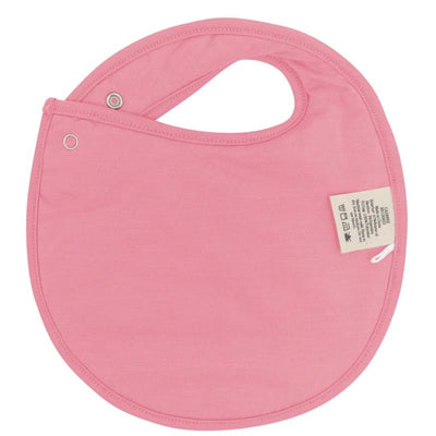 Cushy bib in bow shape, made of soft pink fabric, featuring a snap closure and care label.