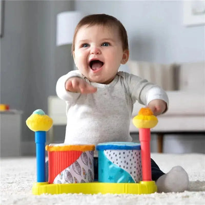 Baby joyfully interacts with the Lamaze Squeeze Beats First Drum Set, featuring colorful drums and playful accessories.