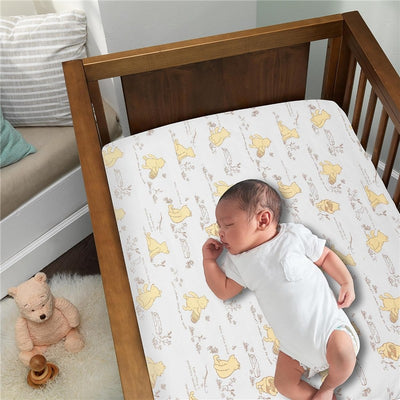 Lambs & Ivy Disney Storytime Pooh crib sheet featuring Winnie the Pooh illustrations, with a sleeping baby in a crib.