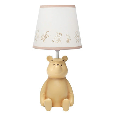 Lambs & Ivy Disney Storytime Pooh Lamp with beige Pooh bear base and a white shade featuring Winnie the Pooh characters.