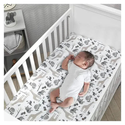 Lambs & Ivy Jungle Baby Crib Fitted Sheet featuring a playful animal pattern, with an infant sleeping peacefully on it.