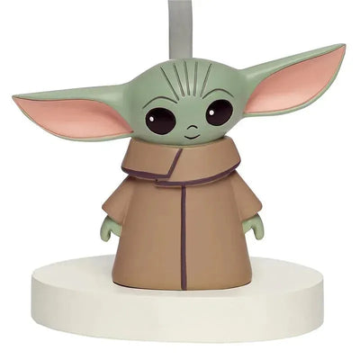 Lamp featuring a figurine of Baby Yoda with large ears, wearing a brown robe, and mounted on a round base.