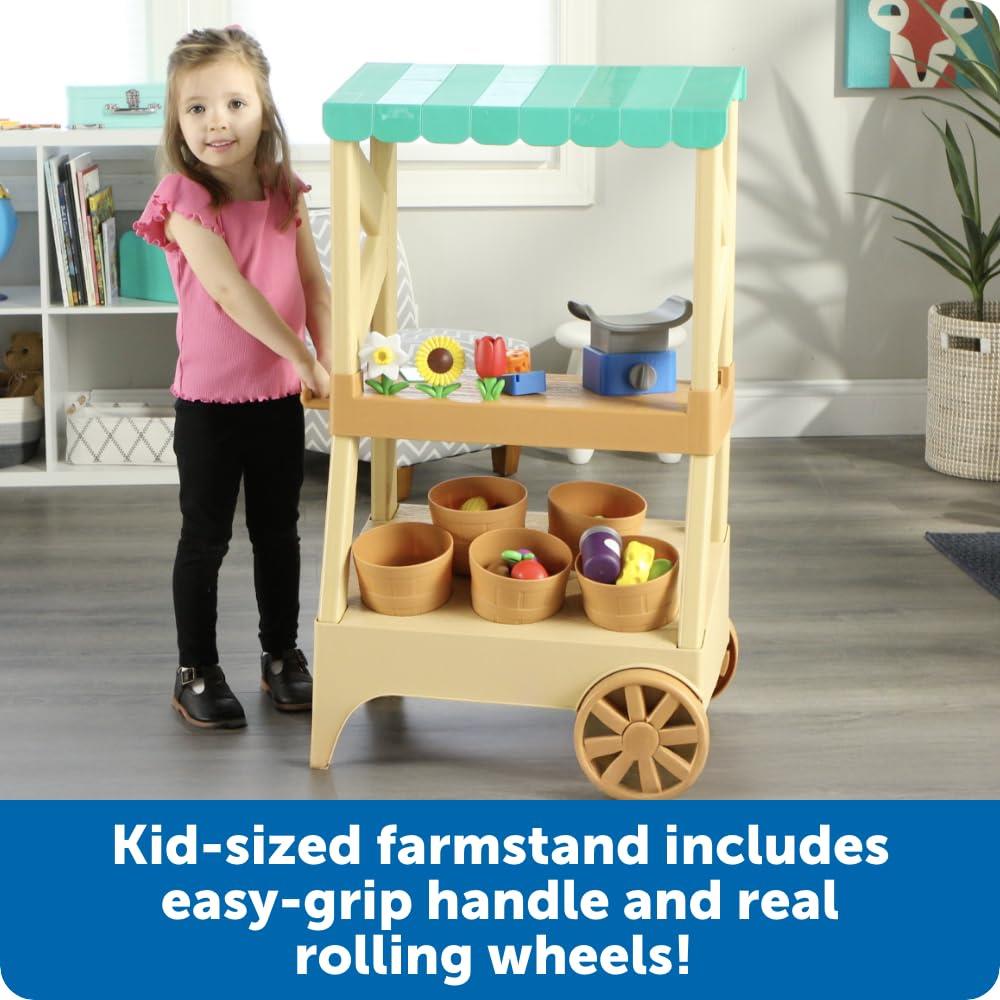 Kid-sized farmstand featuring an easy-grip handle, rolling wheels, and colorful toy fruits and vegetables in baskets.