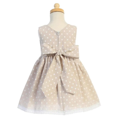 Beige cotton chambray dress for baby girls, featuring white polka dots, a bow at the waist, and a lace hem.