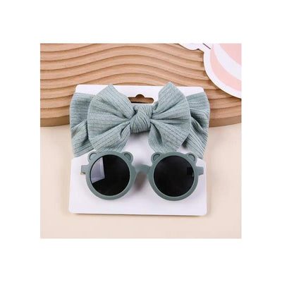 Baby sunglasses with bear ears and a matching light green headband with a large bow, displayed on a white card.