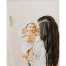 Hooded towel with grey stripes on a baby, being held and smiled at by an adult in a soft setting.
