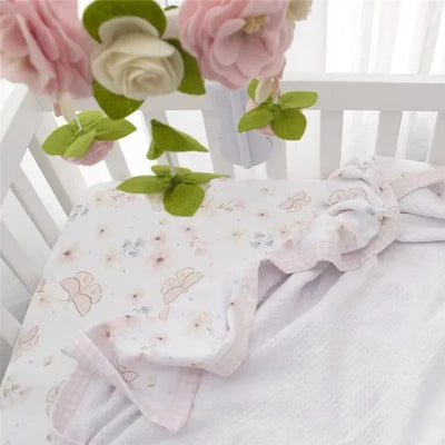 100% cotton jersey crib fitted sheet with a floral design in soft pastel colors, featuring ruffled edges.