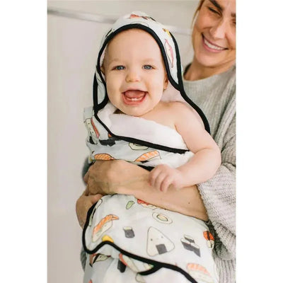 Hooded towel set featuring sushi designs, worn by a smiling baby in the arms of a smiling adult.