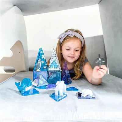 A girl interacts with a 25-piece Magnatiles Arctic Animals set, featuring colorful pyramid structures and animal figures.