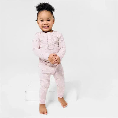 Toddler wearing a light pink Bamboo Pajama Set with a ruffled front, smiling and posed confidently.