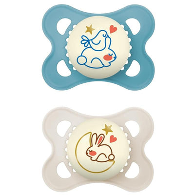 Two pacifiers for infants, one light blue featuring a bird and bunny design, and a cream one with a bunny on a moon, both glow in the dark.