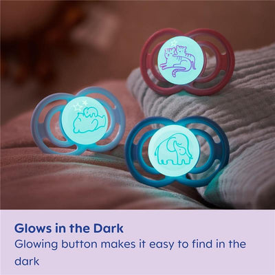 Two glowing baby pacifiers for boys, featuring animal designs (cats and an elephant), on a soft surface with nighttime colors.