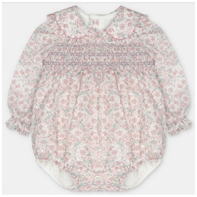 Baby girl romper in woven fabric with smocking, featuring a floral pattern in pink and blue, long sleeves, and a Peter Pan collar.