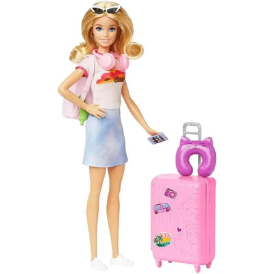 Barbie doll in a casual outfit holds a phone, with a pink suitcase featuring stickers and a purple neck pillow beside her.
