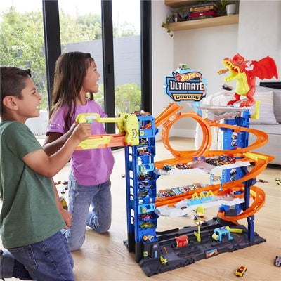 Children play with the Mattel Hot Wheels City Ultimate Garage Track Set featuring cars and a dragon figure.
