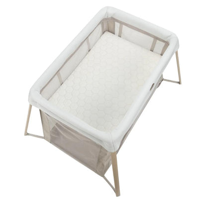 Maxi-Cosi Calao Travel Play Yard in Classic Oat color, featuring a hexagonal patterned mattress and mesh sides for ventilation.