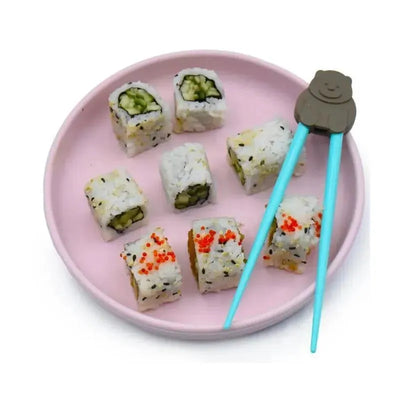 Chopsticks with bear design hold sushi rolls on a pink plate, featuring cucumber and orange roe toppings.
