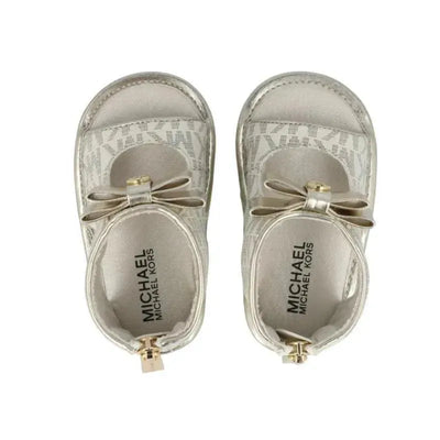 Vanilla-colored crib shoes by Michael Kors featuring a bow detail and logo, designed for infants.