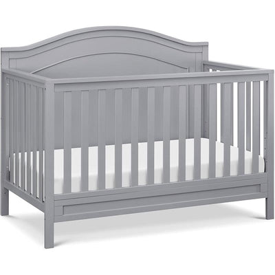 Gray Million Dollar Baby Charlie 4-In-1 Convertible Crib with slatted sides and a curved headboard, featuring a mattress support.