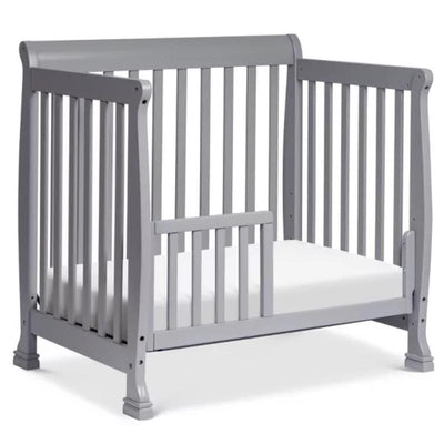 Grey mini toddler bed conversion kit for a crib, featuring slatted sides and a front opening for easy access.