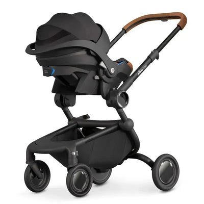 Mima Creo car seat adaptor attached to a sleek black stroller with a brown handle, designed for easy transportation.