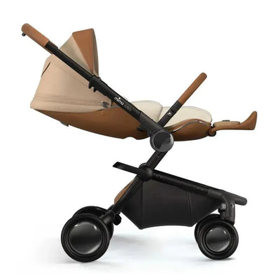 Beige Mima Creo newborn snuggle seat pad with a pillow, featuring a sleek adjustable stroller base and large wheels.
