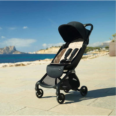 Mima Miro Compact Stroller with black chassis and seat, set against a coastal background.