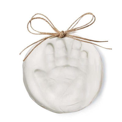 Mud Pie Christmas Ornament Baby Handprint Kit featuring a round white clay ornament with a handprint impression and twine bow.