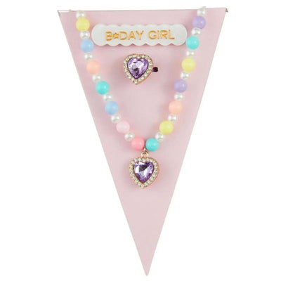 Purple birthday jewelry set featuring a heart-shaped pendant necklace and matching ring, set against a pink background.
