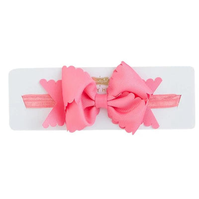 Hot pink scallop bow headband by Mud Pie displayed on a white card, featuring a textured ribbon bow and a coordinating strap.