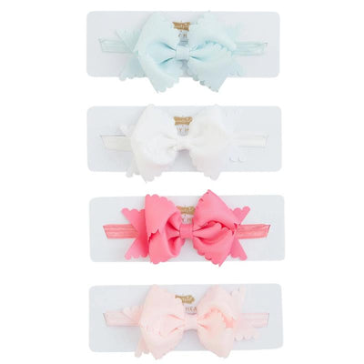 Hot pink scallop bow headband among three other colorful headbands on display cards, showcasing a playful hair accessory collection.