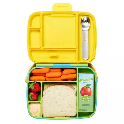 Bento box in green and yellow containing carrots, strawberries, a sandwich, and a juice box, with stainless steel utensils.