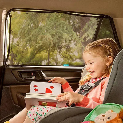 Magnetic stretch-to-fit sun shade installed in a car window, with a smiling girl enjoying a book in her car seat.