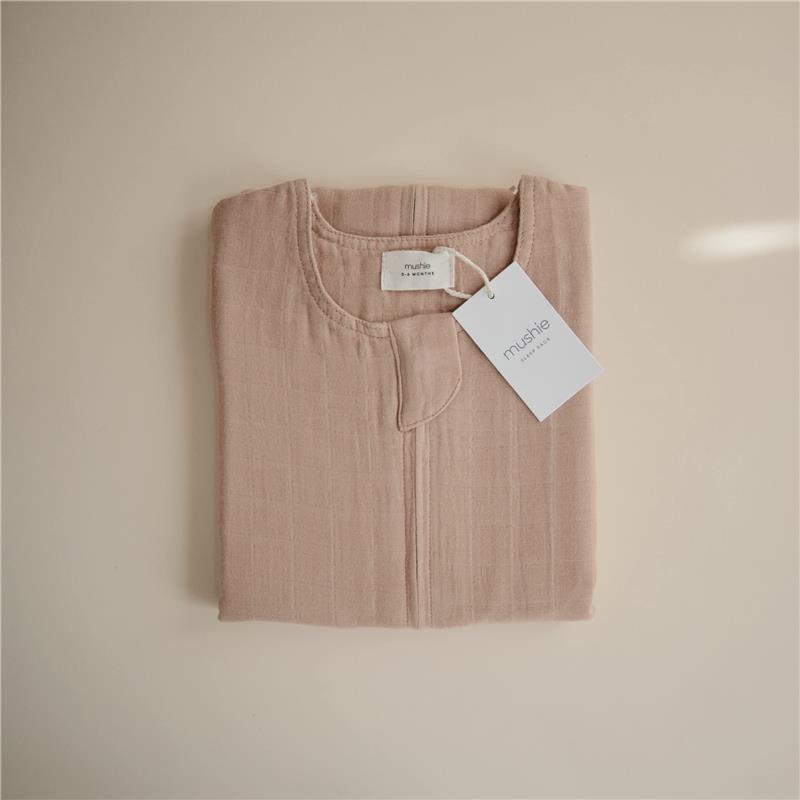100% organic cotton muslin baby wearable blanket in a natural beige color, folded neatly with a tag.