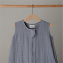 100% organic cotton muslin baby wearable blanket in a soft blue shade hung on a wooden hanger.