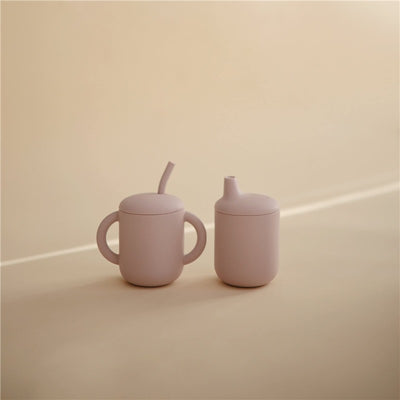 Silicone sippy cup set in soft lilac, featuring a cup with handles and a spout for easy drinking.