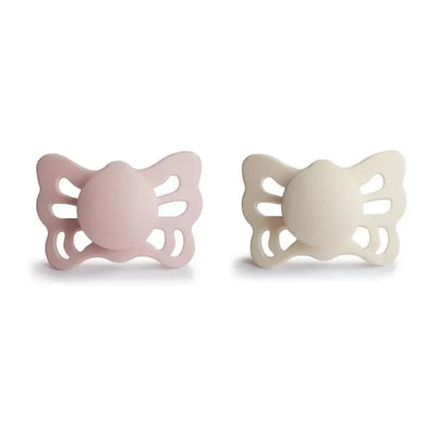 Two anatomical silicone pacifiers in cream and blush butterfly designs, suitable for infants 0 to 6 months.
