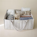 Mushie Baby Diaper Caddy in ivory, filled with neatly rolled swaddles, wipes, and folded blankets for newborn essentials.