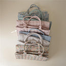Mushie Baby Diaper Caddy in pastel colors, featuring organized compartments and floral patterns for newborn essentials.